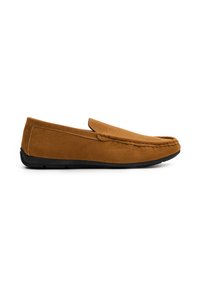 Mocasines de ante marrón sin cordones con una suela de goma negra plana. Textura suave, punta redondeada y costuras visibles a lo largo del borde superior.