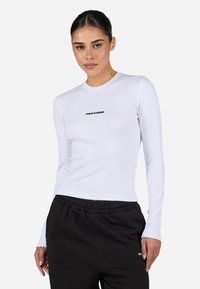Hvit langermet tettsittende t-skjorte med rund hals, med en svart "PEGADOR"-logo på brystet. Materialet framstår som glatt og lett.