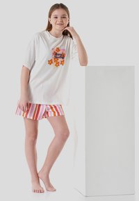 White T-shirt with colorful floral design and "Have A Nice Day" text, paired with pink, orange, and lavender striped shorts.