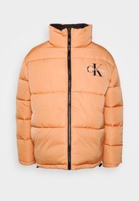 Orange puffer jacket with a high collar, horizontal stitching, and a front zipper. Features Calvin Klein Jeans logo on the chest.
