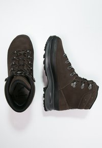 Botas de caminhada castanhas feitas de camurça com uma sólida sola de borracha preta. Apresenta ilhós de metal e costura em contraste. O interior tem um forro suave.