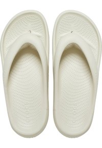 Witte rubberen teenslippers met textuur op de zolen, voorzien van een brede teenpost en een afgeronde bovenkant, ontworpen voor comfort en flexibiliteit.