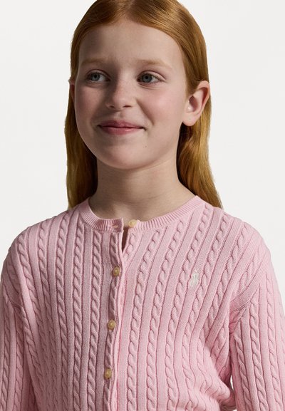 Jersey de punto color rosa claro con patrón de trenzas, cuello redondo y cierre de botones. Presenta botones color crema y un pequeño detalle de logotipo en el pecho.