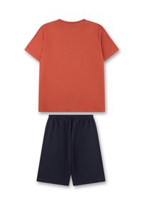 T-Shirt aus verbranntem Orange, aus Baumwolle mit kurzen Ärmeln und Rundhalsausschnitt, kombiniert mit dunkelblauen Baumwollshorts mit elastischem Bund.