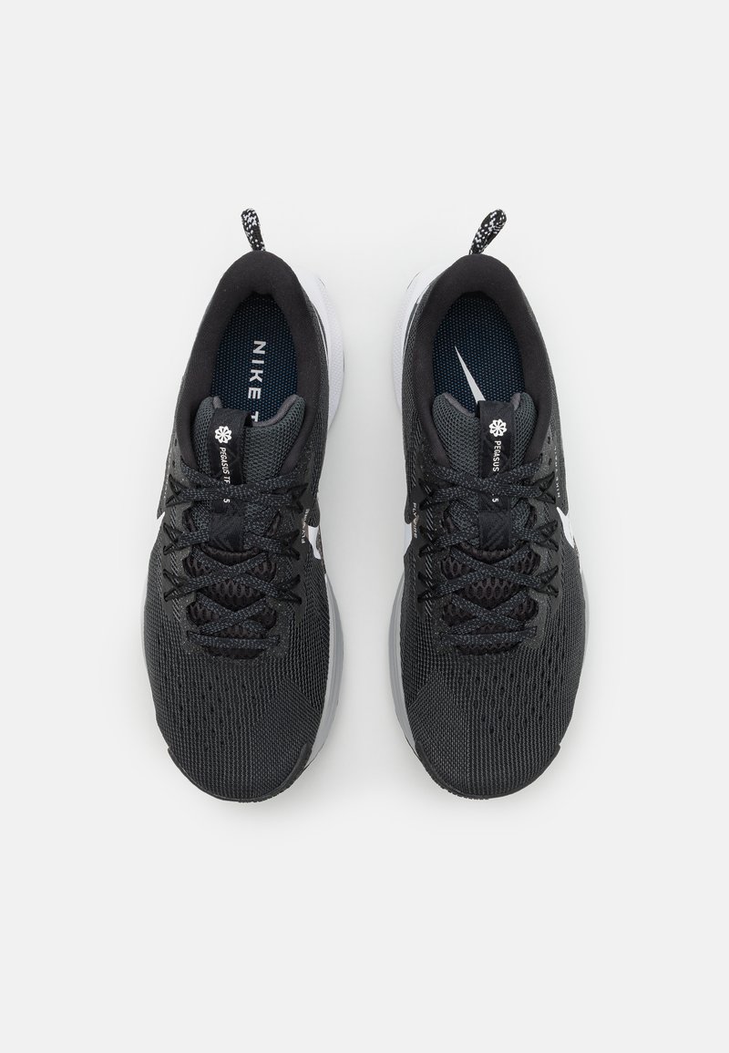 Zapatillas de running Nike con una parte superior de malla transpirable negra, cordones oscuros, suela blanca y un acento reflectante cerca del talón.