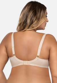 Soutien-gorge beige avec des bretelles réglables, un fermoir à agrafe et des détails en dentelle. Tissu lisse avec un léger éclat et une texture douce.