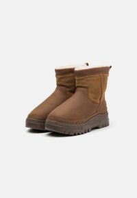 Brune ankelstøvler med en glatt skinnoverdel og myk fôring. Tykk, teksturert gummisåle for godt feste; enkelt design uten synlig utstyr.