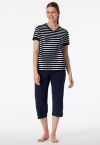 Marinblå och vit randig V-ringad t-shirt parat med enfärgade marinblå capribyxor, båda gjorda av mjukt och bekvämt material.