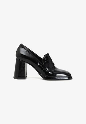 Mocassino da donna in pelle verniciata nera con tacco alto a blocchetto e cinturino decorativo sulla parte superiore, visto di lato.
