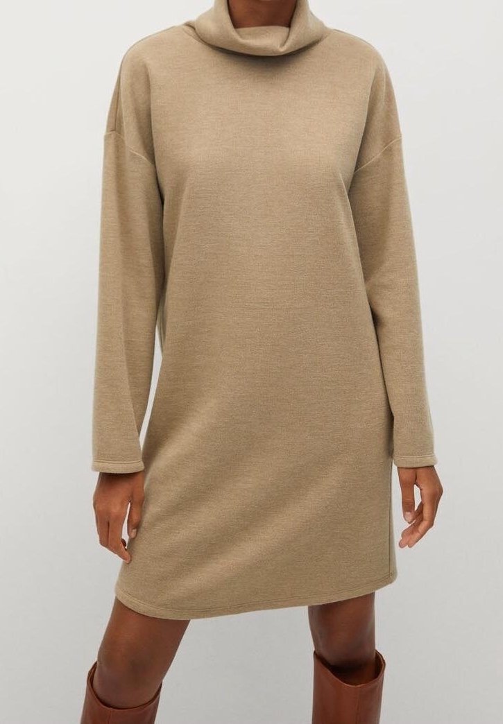 Mini-robe beige à manches longues avec un col roulé ample, portée avec des bottes marron montant jusqu'aux genoux, vue du cou jusqu'à mi-cuisse sur un mannequin.