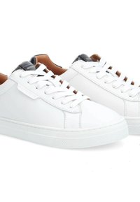 Baskets blanches en cuir avec un laçage à l'avant, semelle en caoutchouc texturé blanche, accent de talon sombre contrastant et finition lisse.