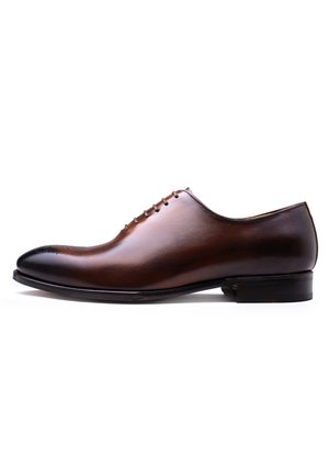 Chaussure habillée en cuir marron avec une texture lisse, un bout arrondi et cinq œillets pour les lacets. Présente des détails de brogue subtils sur le bout.