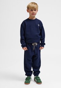Sweatshirt blu navy con maniche lunghe e collo a giro, abbinato a pantaloni jogger coordinati. Presenta una vita regolabile con coulisse e polsini elastici.