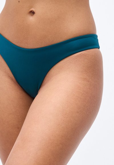 Κατώ μέρος μπικίνι σε τιρκουάζ χρώμα, λείο υλικό, χαμηλή μέση, ελάχιστη κάλυψη και άκοπτες άκρες. Χρώμα δέρματος με ελαφρώς ορατή υφή.