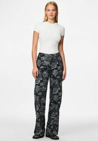 Hlače širokih nogavica s cvjetnim uzorkom u tamnoplavoj boji s sivim i bijelim cvjetovima. Uparene s uskim bijelim T-shirtom. Teksturirana tkanina, ležerni dizajn.