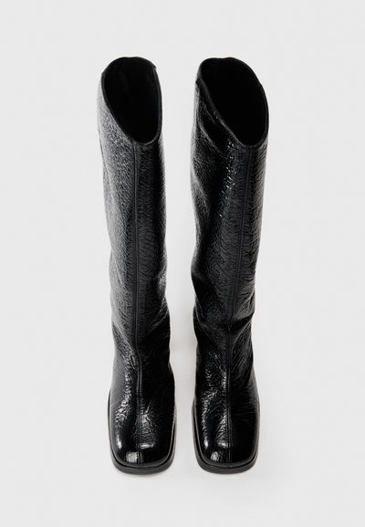 Botas negras hasta la rodilla, hechas de cuero texturizado, con un diseño elegante, punta cuadrada y un acabado liso sin herrajes visibles.