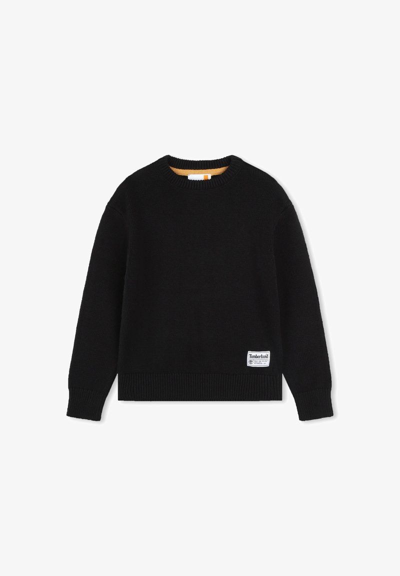 Pull en maille noir avec un col rond, des poignets et un ourlet côtelés, présentant une petite étiquette logo Timberland blanche sur le bas à gauche.