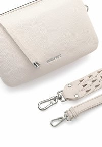 Beżowa, teksturowana torebka na ramię z skóry, z srebrnymi zapięciami, marką "SURI FREY" oraz dwoma odpinanymi paskami, z których jeden ma pleciony detal.