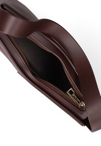 Bruine leren handtas met een ritsluiting, plat ontwerp, gladde textuur en een enkele gebogen handgreep. Interieur is zwart met een ritsvak.