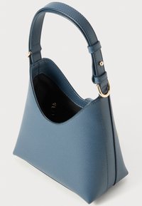 Sac à main en cuir bleu avec un extérieur texturé, une silhouette arrondie et une seule bandoulière réglable. L'intérieur est noir avec une poche zippée.