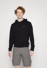 Schwarzer Kapuzenpullover mit Fronttasche und Kordelzug, kombiniert mit grauen Cargo-Shorts mit Seitentaschen und einem kleinen bestickten Detail.