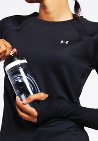 Svart långärmad träningsskjorta med ribbade axelsömmar och tumhål i ärmarna, i kombination med en transparent vattenflaska med svart lock och logotyp.