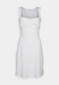 Robe en coton blanche avec un motif texturé et un col à volants. Corsage ajusté menant à une jupe évasée. Design sans manches.