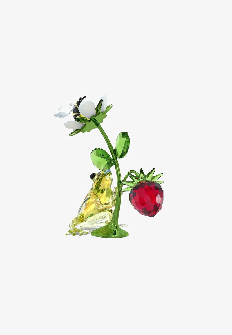 Figurka kryształowa przedstawiająca żółtą żabę, zieloną łodygę, białego kwiata i czerwoną truskawkę. Zauważalne fasetki i błyszczące wykończenia.