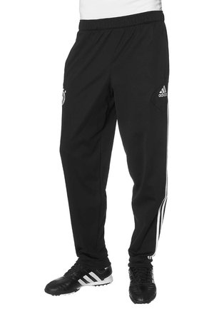 Zwarte Adidas trainingsbroek met witte zijstrepen en logo, gedragen met zwarte Adidas voetbalschoenen.