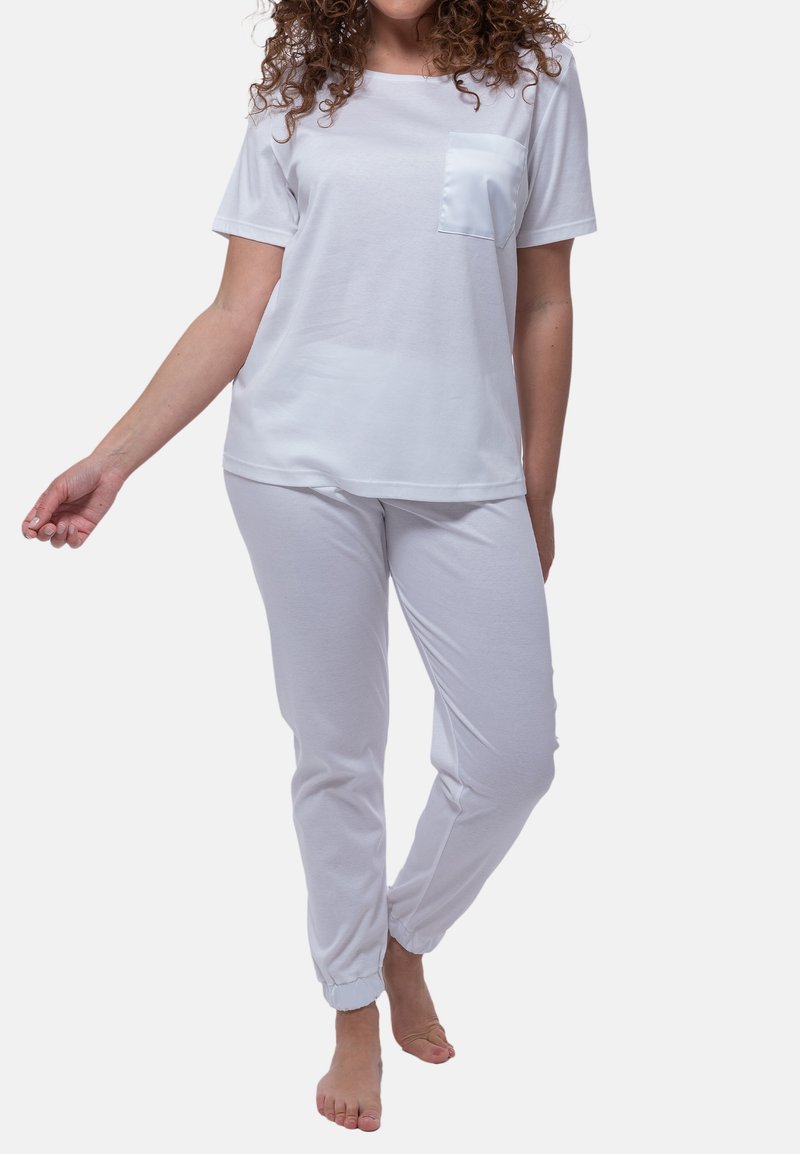 Hvid bomulds t-shirt med en frontlomme, parret med hvide bomulds joggers med elastiske manchetter. Simple design med en afslappet pasform.