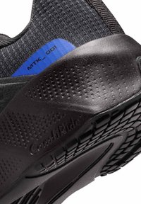 Μαύρος αθλητικός πάτος παπουτσιού με υφή από μαύρο καουτσούκ στη σόλα. Διαθέτει μπλε ετικέτα με την ένδειξη "MTK_001", παρουσιάζοντας ένα σχεδιασμένο καλούπι για στήριξη.