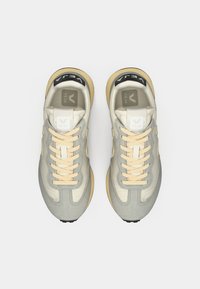 Μπεζ και γκρι αθλητικά παπούτσια με υφή, διαθέτουν μπεζ κορδόνια, μαύρο λογότυπο στη γλώσσα και λαστιχένια σόλα.