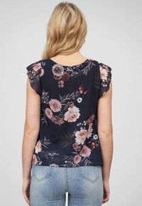 Blouse à imprimé floral en marine, dotée de manches courtes à volants, d'un col rond et de fleurs multicolores sur un tissu doux.