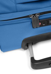 Valigia di stoffa blu con doppio zip, manico metallico retraibile e dettagli neri. Presenta una serratura a combinazione e un'area di presa testurizzata.