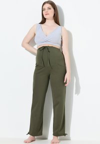 Šedý zkrácený top a olivově zelené kalhoty s vysokým pasem a stahovacím páskem. Kalhoty mají boční kapsy a zřasené lemy se stahovacími šňůrkami. Měkká textilie.