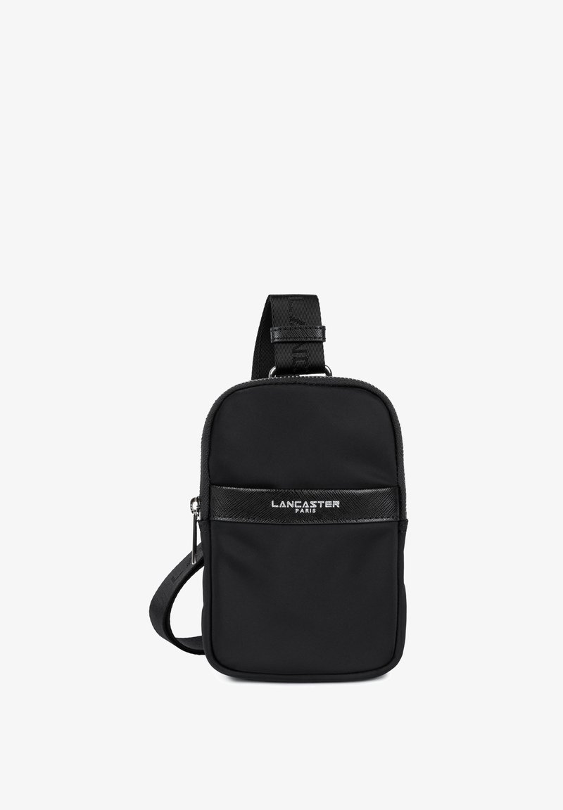 Sac bandoulière en nylon noir avec une sangle texturée, fermeture éclair et un panneau logo avant. Il présente une forme rectangulaire compacte et un design minimaliste.