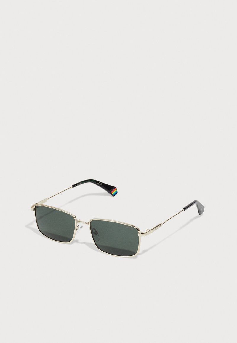 Rectangular sunglasses with dark green lenses, gold metal frame, thin arms, and a black tip featuring a rainbow accent.