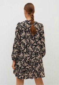 Schwarzes Blumenkleid mit einem geschichteten Rock, langen Puffärmeln und einem strukturierten Stoff mit einem beige-blumigen Muster.