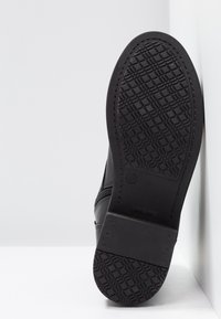 Czarne skórzane botki za kostkę z teksturowaną gumową podeszwą, z boku zapinane na zamek oraz gładkim wykończeniem. Podeszwa ma wzór siatki dla lepszej przyczepności.