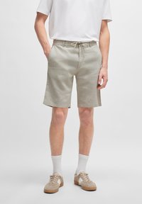 Pantaloni corti beige chiaro con vita regolabile tramite cordoncino, dotati di tasche laterali e vestibilità comoda. Realizzati in un tessuto testurizzato per offrire comfort.