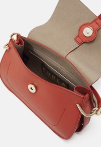 Sac bandoulière en cuir rouge avec ferrures dorées, rabat ouvert dévoilant l'intérieur en suède beige et le logo Furla à l'intérieur.