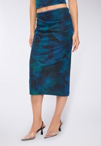 Spódnica o średniej długości, wykonana z gładkiej, ciemnoniebieskiej tkaniny w kwiatowy wzór; połączona z przezroczystymi, plastikowymi butami ozdobionymi koralikami.