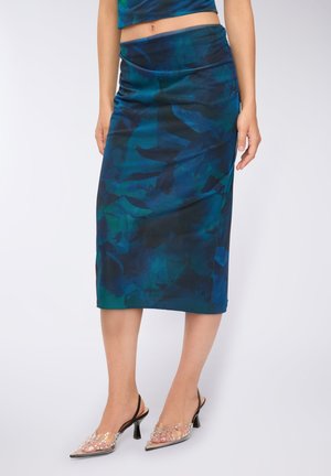 Spódnica o średniej długości, wykonana z gładkiej, ciemnoniebieskiej tkaniny w kwiatowy wzór; połączona z przezroczystymi, plastikowymi butami ozdobionymi koralikami.