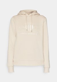 Sweat à capuche beige avec logo embossé à l'avant indiquant « GANT 1949 American Sportswear » et fermeture à cordon.