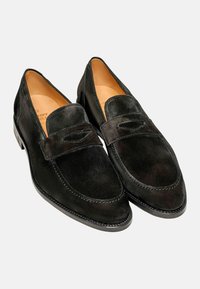 Schwarze Wildlederloafers verfügen über ein dekoratives Band und gestickte Details. Die Sohlen sind glatt mit einer leichten Textur für besseren Halt.