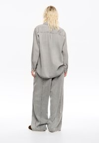 Gray denim shirt and wide-leg pants, featuring straight seams, button cuffs, and a curved hem. The fabric has a soft texture with a faded finish.