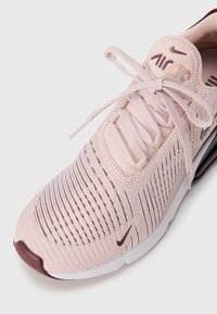 Nike Air Max 270 u svijetlo rozoj boji, sa prozračnim mrežastim gornjim dijelom, vezicama i teksturiranim uzorkom. Akcenti u tamnijim nijansama.