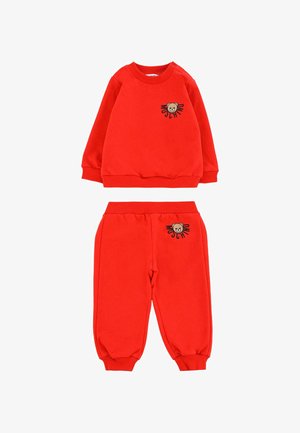 Rode katoenen kinderkostuum met een sweatshirt met geribbelde manchetten en een geborduurd berenmotief, vergezeld van bijpassende broek.