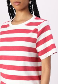 Camiseta de rayas rojas y blancas, de manga corta, con escote redondo, material de algodón suave, costura visible a lo largo del escote, ajuste casual.