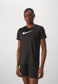 Črna atletska majica s kratkimi rokavi in okroglo ovratnikom. Na sprednji strani je bel Nike logotip. Prilegajoča se zasnova, izdelana iz gladkega materiala.